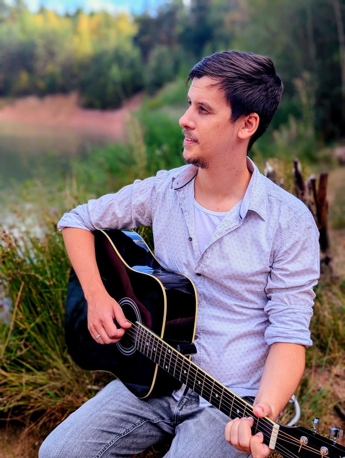 Fabian Kirchner mit seiner Akustikgitarre am See